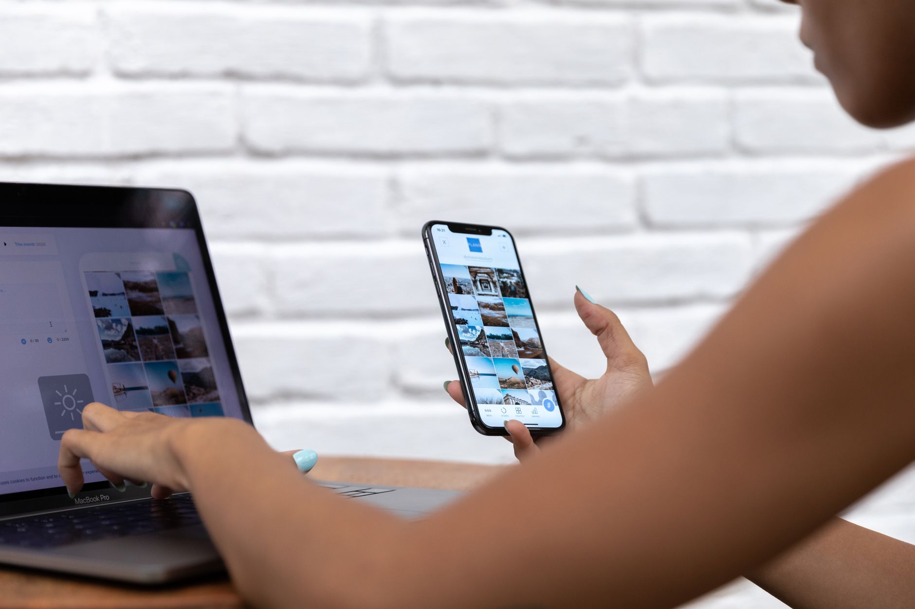A person scheduling social media content on a laptop while holding a smartphone showing a feed